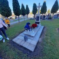 Zdjęcia przedstawiają uczniów w czasie składania kwiatów i zapalania zniczy na grobach. (5)