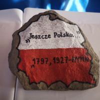 Kamień z namalowanym biało-czerwonym konturem Polski, w środku napis: 